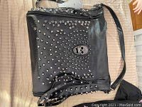 Front view of the black synthetic leather tote purse showing skull design and stud embellishments.