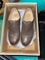 Pair of grey leather slip-on Clarks shoes in original box viewed from top showing shoe uppers.