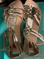 Top view of gold metallic strappy flat sandals showing design and condition.