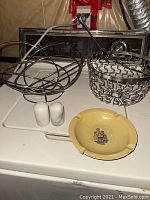 View showing metal fruit bowls, marble salt and pepper shakers, ashtray arranged on a white surface