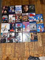 Photo showing 22 assorted DVD cases arranged on the floor, titles visible.