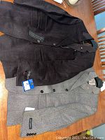 Two Bellissimo suit jackets, one brown short wool and cashmere, the other grey 100% wool Cedar model, laid on table