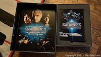Boxed collector's book and DVD case with Battlestar Galactica branding and imagery.