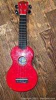Full view of red Mahalo ukulele showing body, neck, fretboard, and headstock with tuning pegs.
