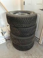 Stack of four snow tires on steel rims from side view
