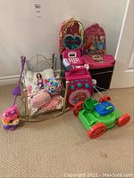 Full view of all items including backpacks, stuffed animals, toy karaoke machine, toy washer, doll, and toy lawn mower.