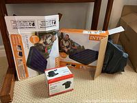 Two Intex twin size inflatable mattresses in original boxes with one mattress partially visible, along with the black electric air pump beside the boxes.