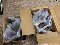 Two cardboard boxes filled with clear plastic hangers with metal hooks, showing the quantity and condition.