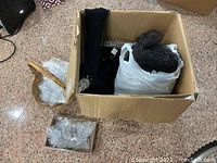 Cardboard box containing black string tassels and glittery butterfly ornaments in plastic.