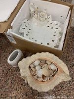 Main image showing the ceramic shell-shaped fruit bowl filled with seashells, small white ceramic holder, and white ceramic plate with shell decoration stored in a box