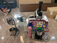 Wide view of the lot showing chrome Salton drink mixer, NutriBullet style juicer, Magic Bullet blender cups and accessories with pink base, and compact black electric grill.