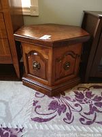 Hexagon wooden side table with visible scratches and a warm wood finish on a patterned rug.