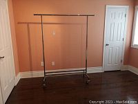 Full view of metal coat rack against wall showing size and design.