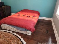 Queen size mattress and box spring from a front angle with floral bedding visible