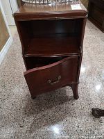 Full front view of wooden side table with door opened to show interior storage and shelf.