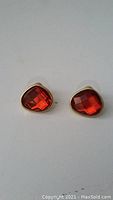 Clear photo showing both earrings with red faceted stones in gold-tone metal.