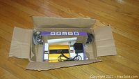 Boxed cellular signal booster kit showing gold repeater unit with cables in purple retail box inside brown shipping box.