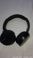 Black Sony wireless Bluetooth over-ear headphones with visible plastic repair on the headband on one side. Ear cups padded with one side not folding inwards. Sony logo on one ear cup.