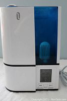 Front view of white and blue TaoTronics ultrasonic humidifier showing LED display and control panel with buttons and humidistat.