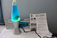 14.5 inch lava lamp with blue liquid and green wax inside, silver base and cap, shown with original box and care instructions on flat surface.