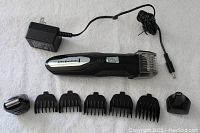 Remington PG6027 electric hair clippers with charger and seven attachments laid out on white surface