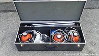 Top view of black hinged carrying case open showing 3 orange Ianiro Varibeam 1000w heads stored inside compartments with cables and accessories.