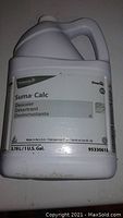 One gallon white plastic jug labeled Suma Calc D5 descaler with handle and cap, placed on white surface.