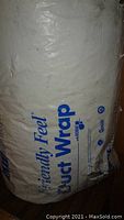 Close-up photo of packaged white Knauf Friendly Feel Duct Wrap showing brand and product information.