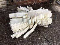 Two sets of white fire hoses, coiled and secured with ties, lying on the pavement.