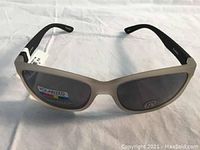 Front view of Joe Fresh sunglasses with polarized dark lenses and beige frame showing stickers for polarized and UV protection