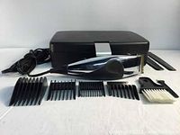 Remington hair clipper with power cord, five black plastic comb attachments, cleaning brush, tool, two black combs, and black case
