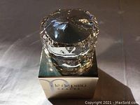 Front angle of the 2mL Intensive Eye Contour Cream jar on top of its box, showing faceted clear container and golden box beneath.