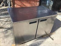 Image of stainless steel commercial under counter cooler/freezer showing front and side surfaces, flat top, and two recessed handle doors