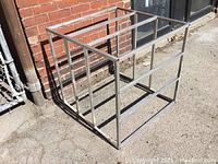 Photo showing welded aluminum square tube frame from an angled side view outside a brick building.