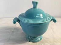 Front view showing the turquoise sugar bowl with lid in place, glossy finish, molded handles, footed base with five rings visible