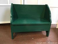 Front angled view of the green wooden toddler bench showing seat, backrest and armrests.