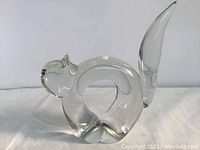 Front angle of clear crystal cat paperweight showing rounded head, looped body and upright tail.