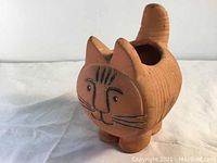 Side and front views of a small terracotta cat-shaped pottery planter with black hand-painted face details.