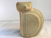 Front view of sandstone cat figure showing carved facial features and chipping at ears.