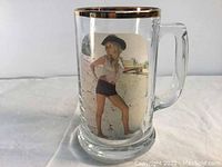 Photo showing front side of the clear glass beer mug with a gold rim and printed pinup girl image