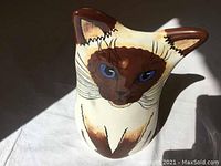 Front close-up of the hand painted Siamese chocolate point cat face with blue eyes and brown features, showing detail and condition.