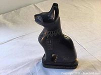 Side view of the black basalt stone handmade vintage Egyptian cat sculpture showing hieroglyphic details on the side and a smooth polished finish.