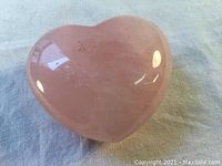 Top-down view of the polished pink marble heart paperweight showing smooth surface and light reflections.