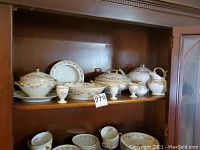 Photo of Limoges china displayed on wooden shelf, showing covered vegetable dish, tea pot, gravy boat, creamer, small covered dish, saucers and egg cups.