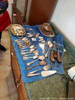 Full collection layout on a countertop showing all silver plated serving pieces, cutlery, bone handled carving knives, and serving dish.