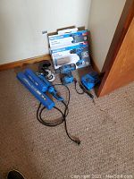 Full view of Mastercraft drills, angle grinder with blades, torque wrenches in blue cases, and battery charger laid on carpet.