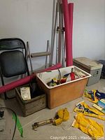 View of folding chair, swim noodles, sailors flags, a fiberglass bin, and assorted boating supplies on the floor.