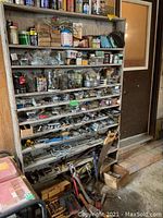 Full view of 6-tier metal shelving with assorted hardware and tools on shelves and floor