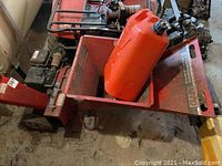 Angled view of red MTD chipper/shredder with gas can placed in hopper intake