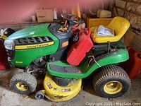 Front left view of mower showing D120 decal, mowing deck, and gas can strapped to fender